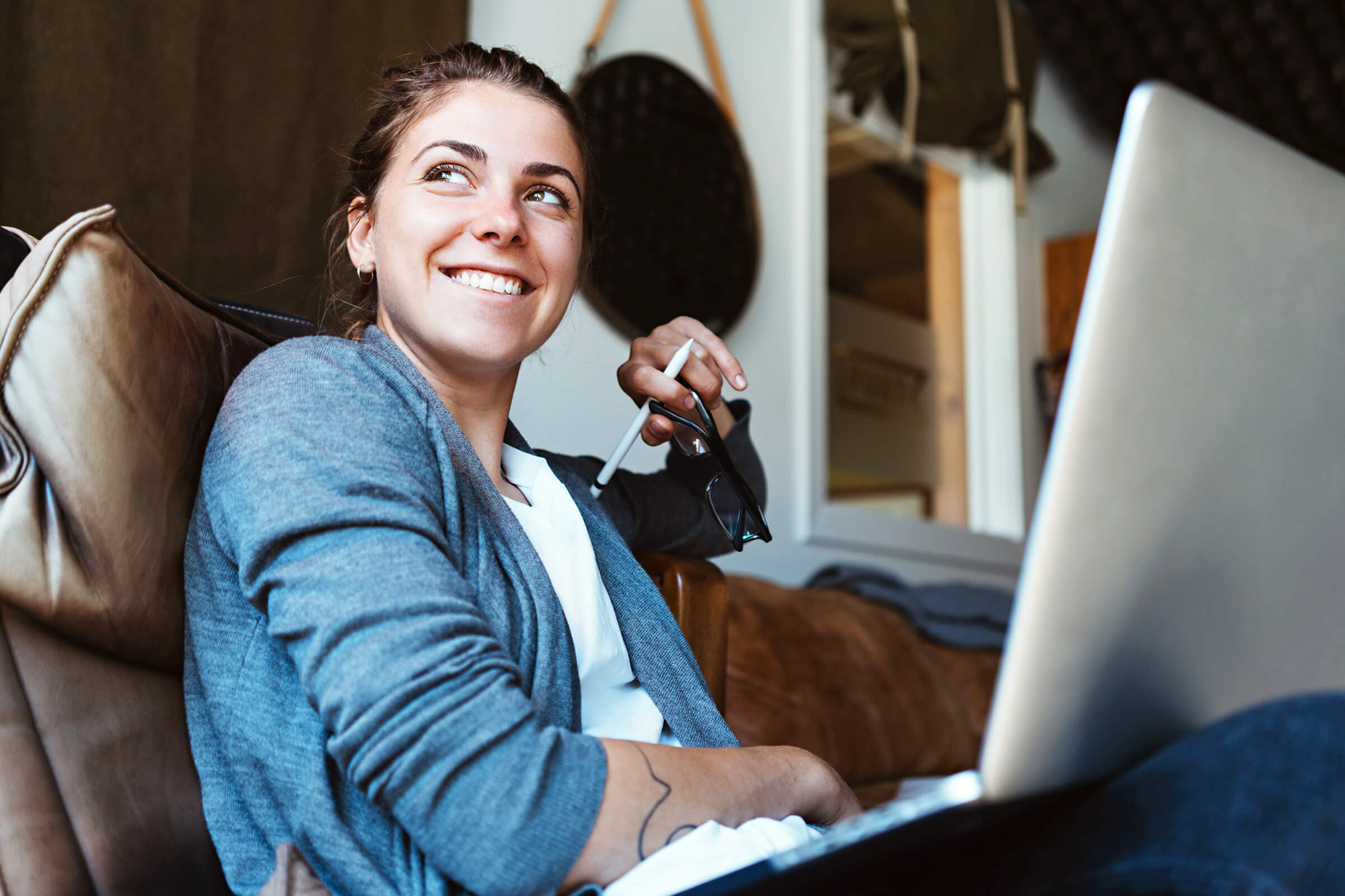 Junge Dame arbeitet am Laptop und steht für die Wohnhausversicherung.