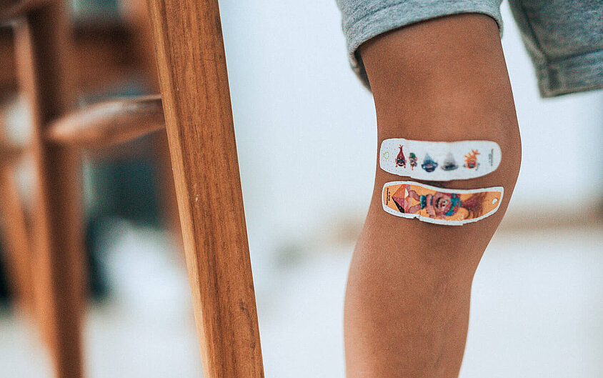 Verletztes Knie eines Kindes mit einem Pflaster, weist auf die DONAU Krankenversicherung für Kinder hin.