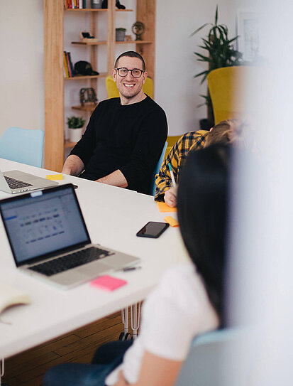 Junger Unternehmer diskutiert in einem Meeting über die Abfertigung seiner Mitarbeiter:innen.