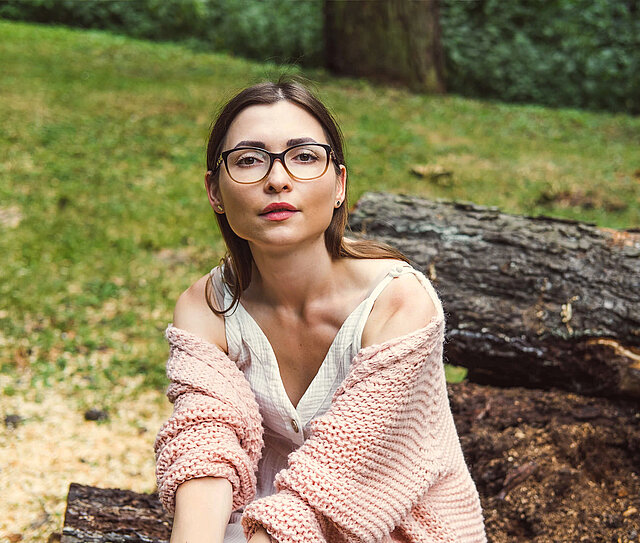 Junges Mädchen mit Brille ist in der Natur und steht für eine Sonderklasseversicherung für Einsteiger.