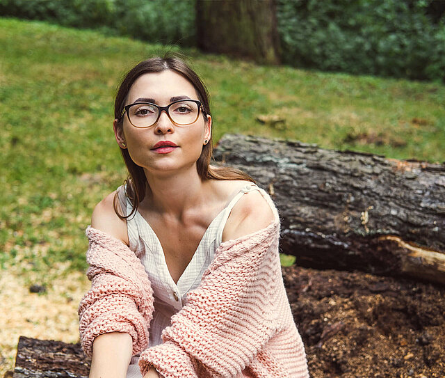 Junges Mädchen mit Brille ist in der Natur und steht für eine Sonderklasseversicherung für Einsteiger.