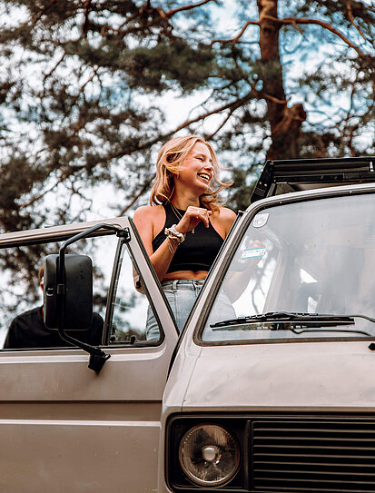 Junge Dame befindet sich in einem alten Bus und denkt über eine Auslandsreise Krankenversicherung nach.