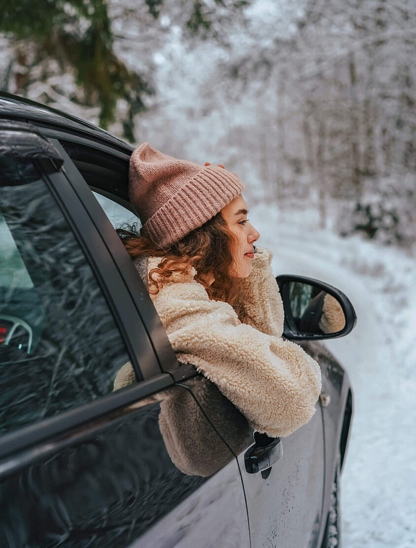 Junge Dame sitzt am Beifahrersitz eines Autos und muss sich aufgrund der Insassenunfallversicherung keine Sorgen machen.