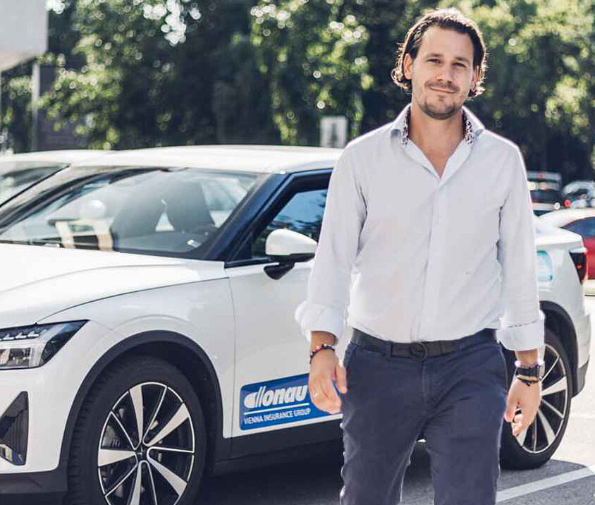 Person in weißem Hemd steht vor einem DONAU gebrandeten Auto. 