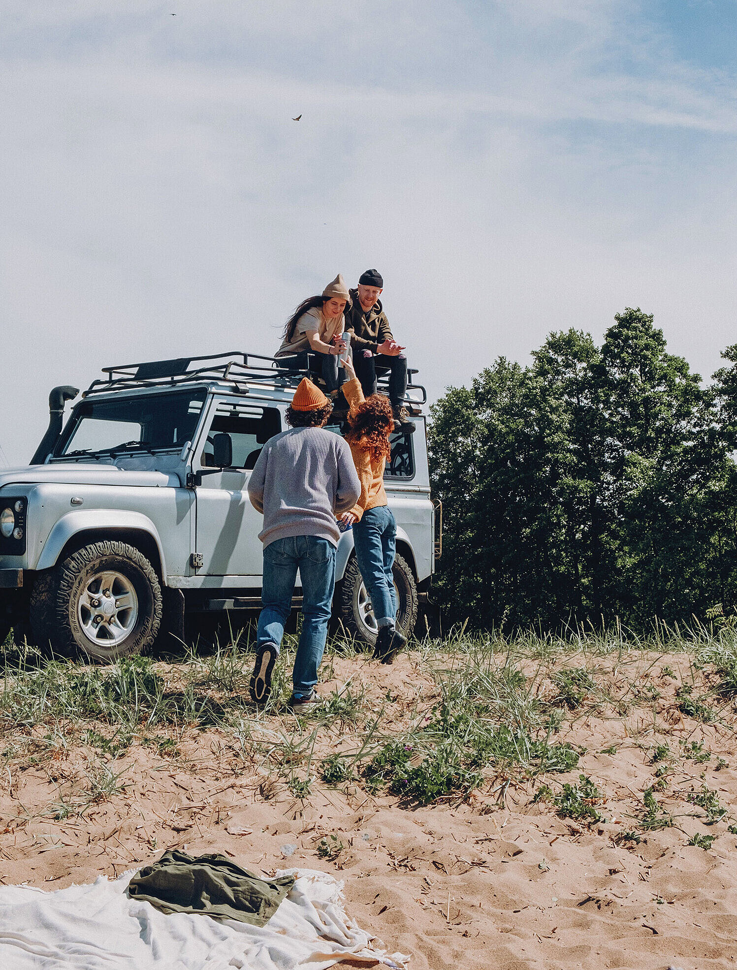 Mehrere Personen packen Gepäck auf ein Geländefahrzeug im Grünen.