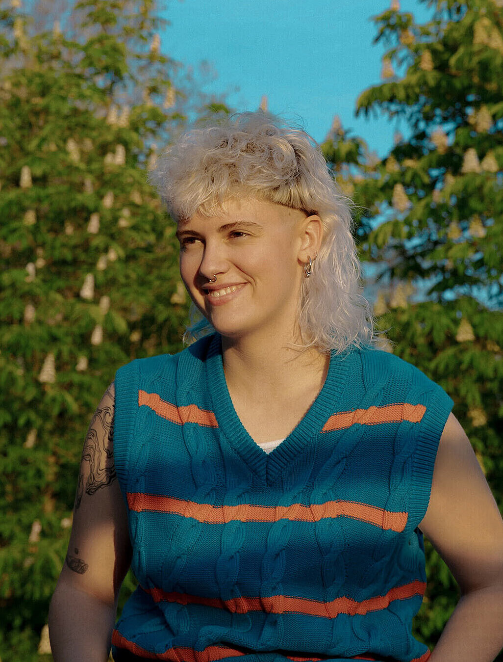 Blonde Frau sitzt in ihrem Obstgarten und überlegt, ob eine nachhaltige Vorsorge für sie sinnvoll ist.