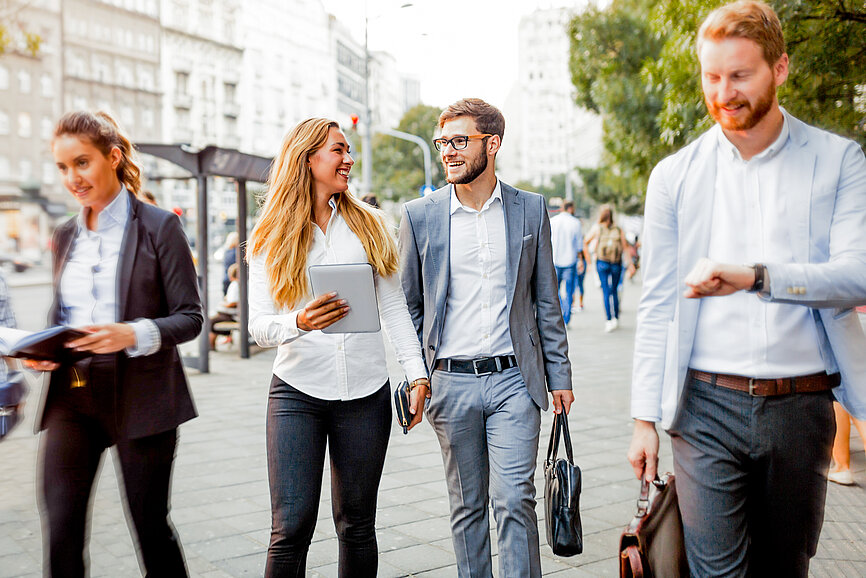 Mann und Frau in Business Look sparzieren und sprechen über die Betriebliche Kollektivversicherung ihres Arbeitgebers.