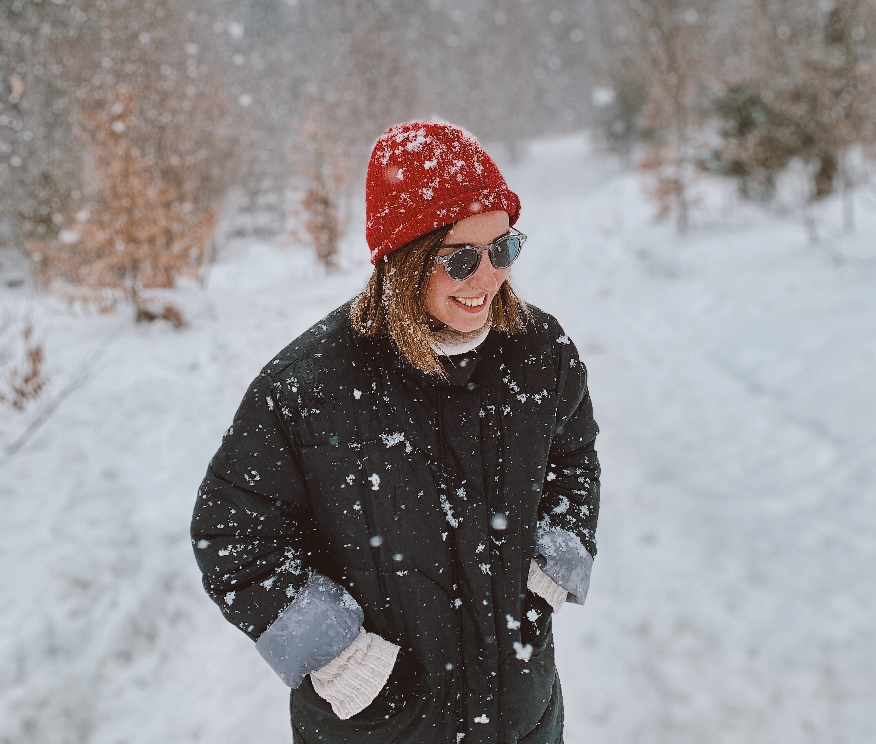 Junge Frau genießt die Winterlandschaft und möchte sich über die Unfallvermeidung im Winter informieren.